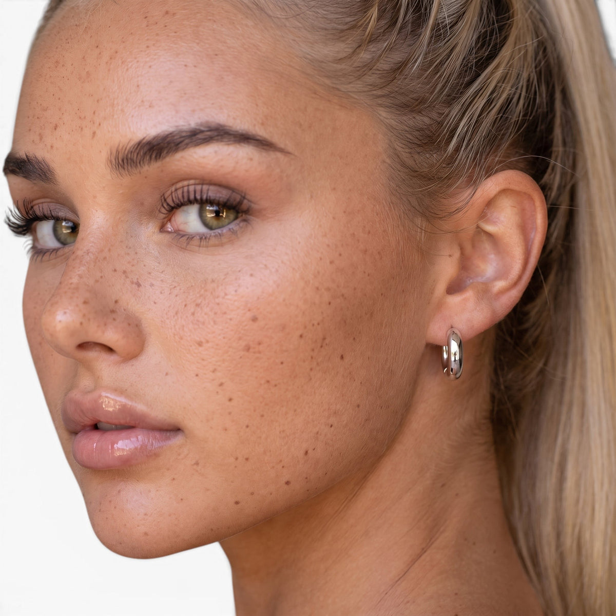 Evervanta dainty silver huggie hoop earrings worn by a woman with a high ponytail, showing a minimalist everyday style