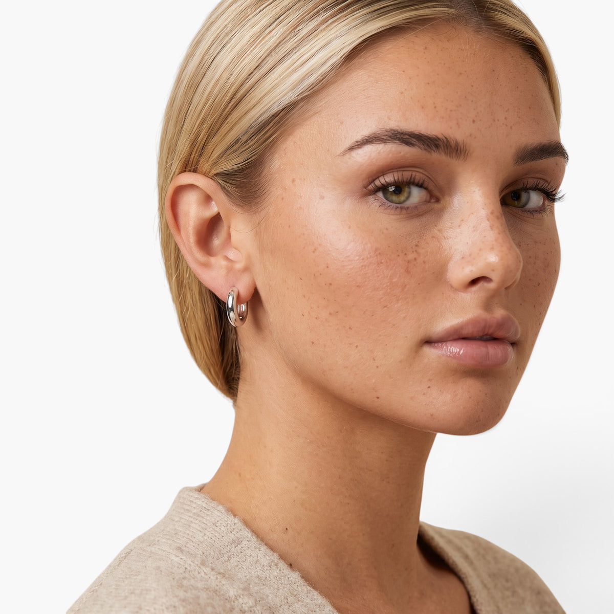 Evervanta dainty silver huggie hoop earrings worn by a woman with blonde hair, showing a minimalist everyday style.