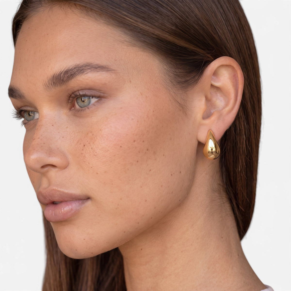 Evervanta gold teardrop earrings worn by a woman with long brown hair, featuring a polished stainless steel finish.