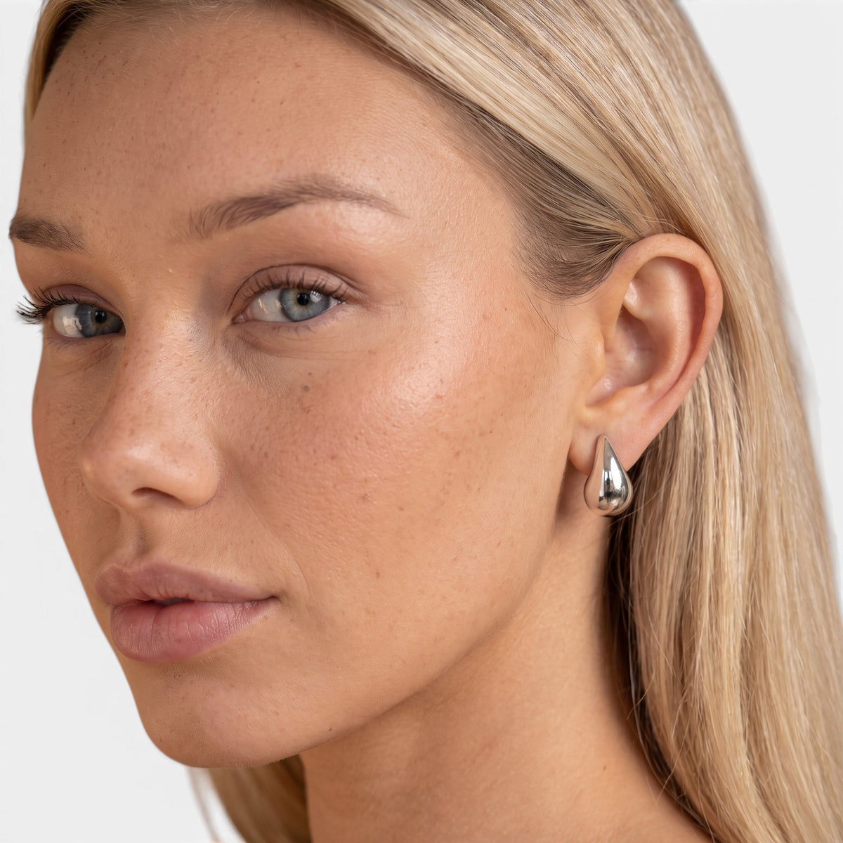 Evervanta silver teardrop earrings worn by a blonde model, featuring a polished stainless steel raindrop design.