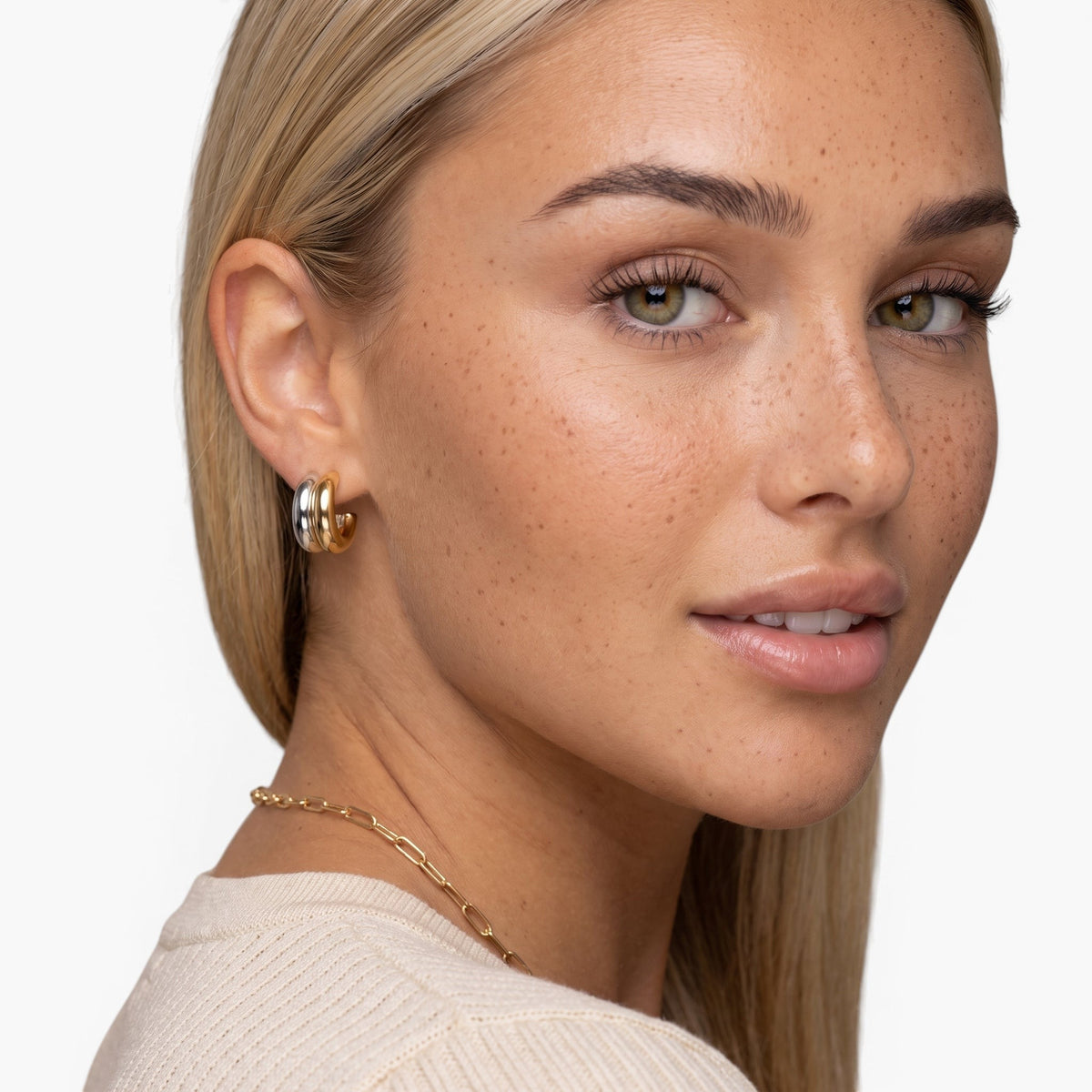Evervanta two-tone huggie hoops featuring 18K gold and silver plating worn by a blonde woman.